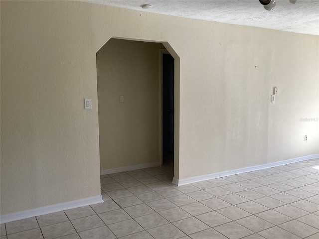 tiled empty room with a textured ceiling