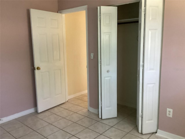 unfurnished bedroom featuring a closet and light tile floors