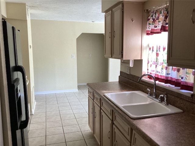 kitchen featuring a textured ceiling, sink, stainless steel fridge, and light tile floors