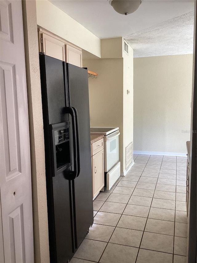 kitchen with black refrigerator with ice dispenser, electric range, light tile floors, and cream cabinetry