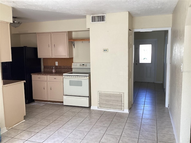 kitchen featuring black fridge, white electric stove, a textured ceiling, and light tile floors