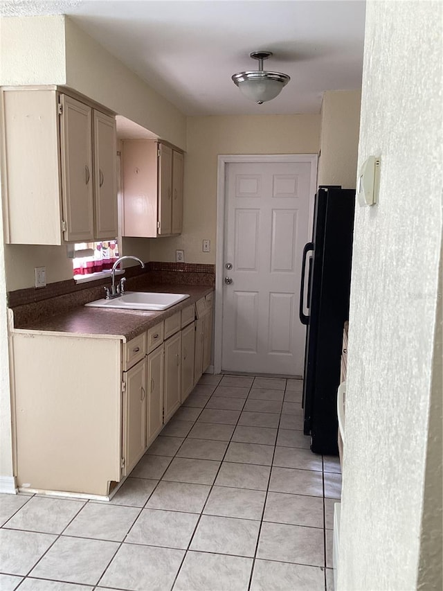 kitchen featuring black fridge, sink, and light tile flooring