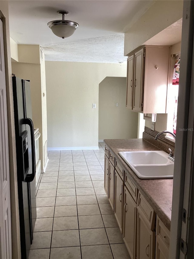 kitchen featuring sink, stainless steel fridge, and light tile flooring