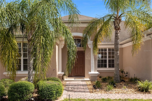 property entrance with a shingled roof and stucco siding