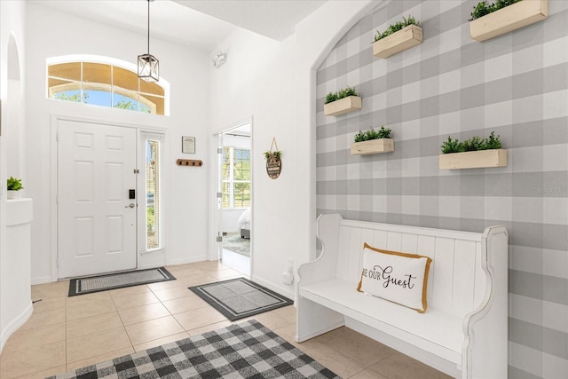 entryway featuring light tile patterned floors, an accent wall, baseboards, and wallpapered walls