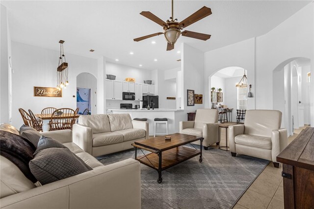 tiled living room with ceiling fan and a towering ceiling