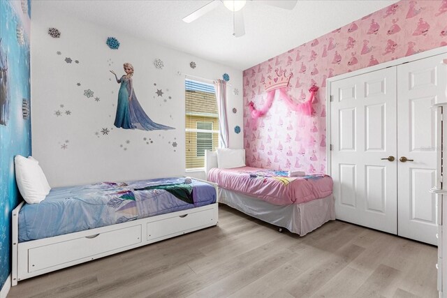 bedroom with ceiling fan, light wood finished floors, a closet, and wallpapered walls