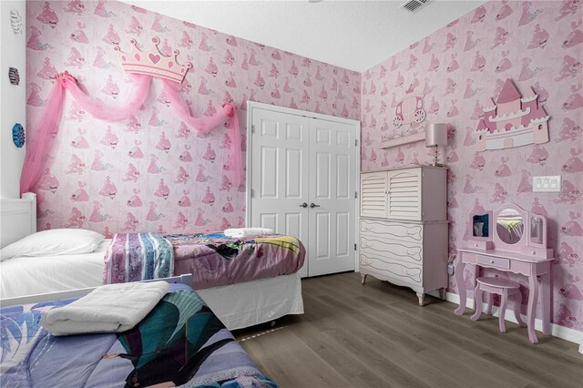 bedroom with dark wood finished floors, a closet, a textured ceiling, baseboards, and wallpapered walls