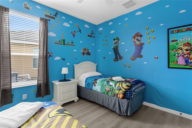 bedroom featuring light wood-style floors, visible vents, baseboards, and a ceiling fan