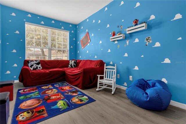 rec room with an AC wall unit, wood finished floors, and baseboards