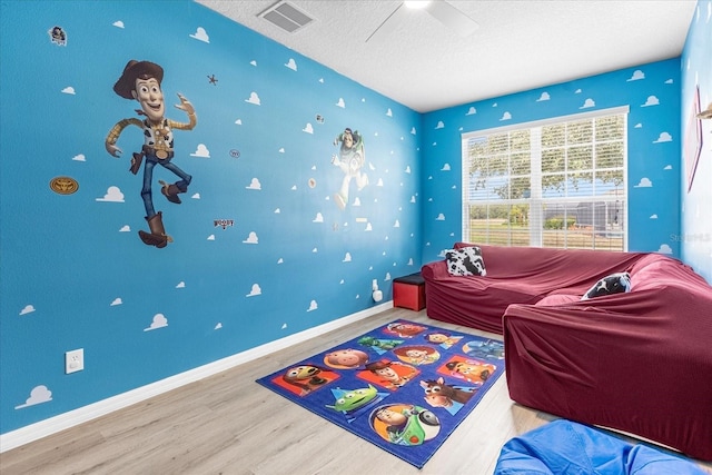 game room with ceiling fan, wood-type flooring, and a textured ceiling