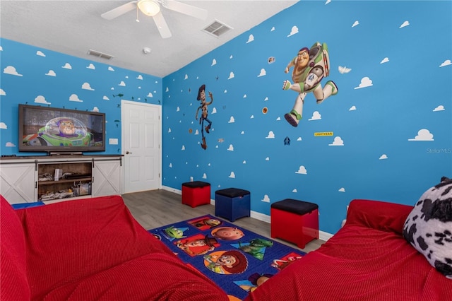 living room featuring a ceiling fan, wood finished floors, visible vents, and baseboards