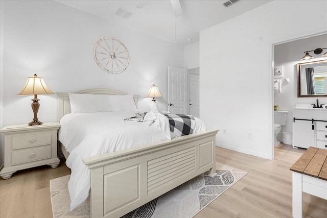 bedroom with ensuite bathroom, ceiling fan, light hardwood / wood-style floors, and sink