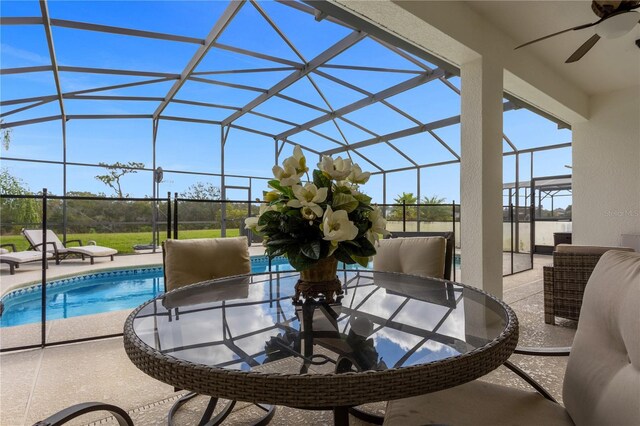 view of patio with a ceiling fan, glass enclosure, and an outdoor pool