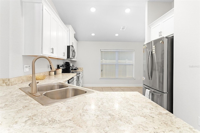 kitchen featuring sink, white cabinets, light tile patterned flooring, and appliances with stainless steel finishes