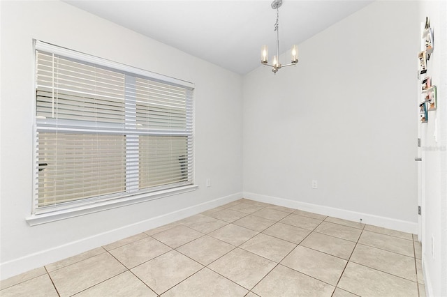 empty room with a chandelier and light tile patterned floors