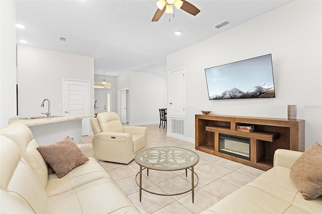 tiled living room with ceiling fan and sink