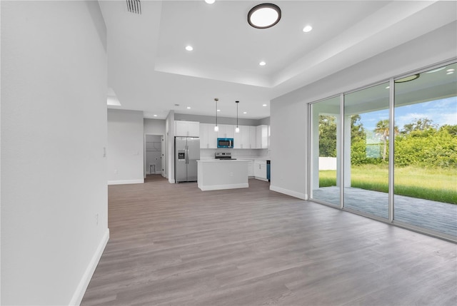 unfurnished living room featuring light hardwood / wood-style floors and a tray ceiling