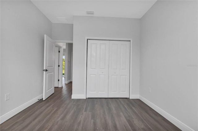 unfurnished bedroom with dark hardwood / wood-style floors and a closet