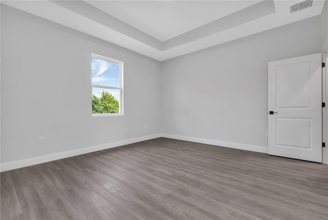 empty room with hardwood / wood-style flooring and a tray ceiling