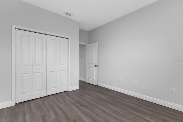 unfurnished bedroom with dark hardwood / wood-style floors and a closet