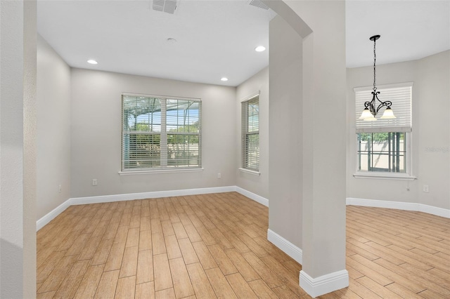 empty room with a notable chandelier and light wood-type flooring