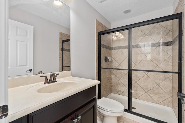 bathroom with a textured ceiling, tile floors, a shower with door, large vanity, and toilet