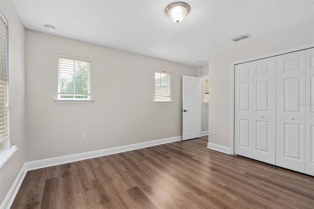 unfurnished bedroom featuring dark hardwood / wood-style floors, a closet, and a textured ceiling