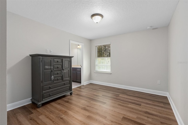 bedroom with hardwood / wood-style floors, ensuite bath, and a textured ceiling