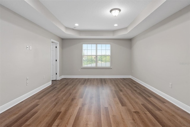 unfurnished room featuring a tray ceiling and wood-type flooring