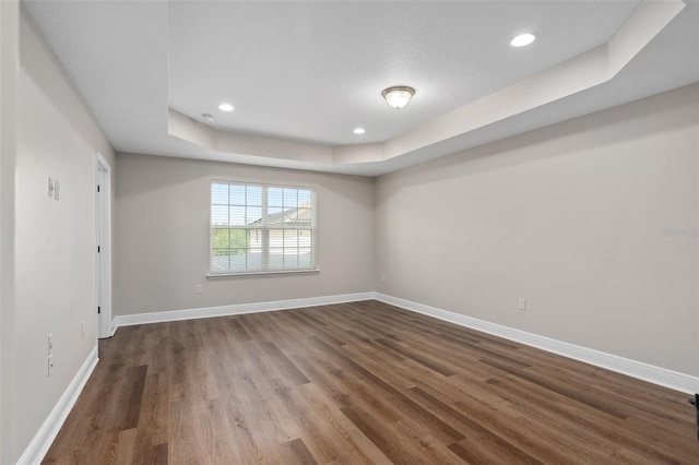 empty room featuring a tray ceiling and dark hardwood / wood-style flooring