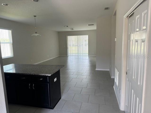 kitchen featuring light stone countertops, plenty of natural light, light tile patterned flooring, and pendant lighting