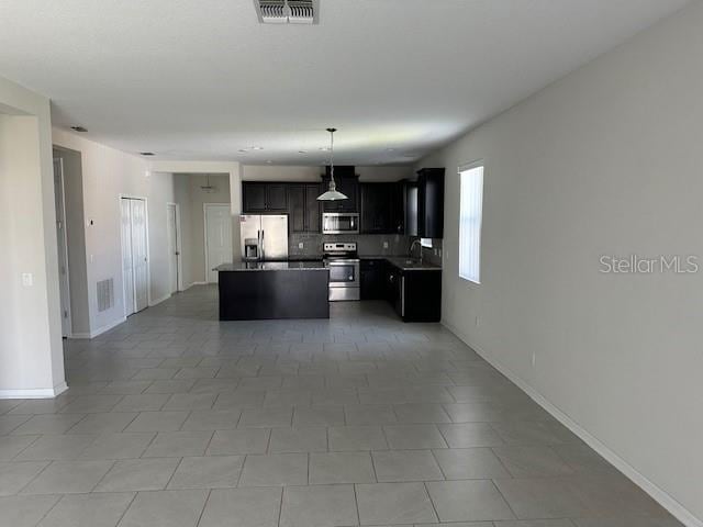 kitchen with a center island, backsplash, hanging light fixtures, sink, and appliances with stainless steel finishes