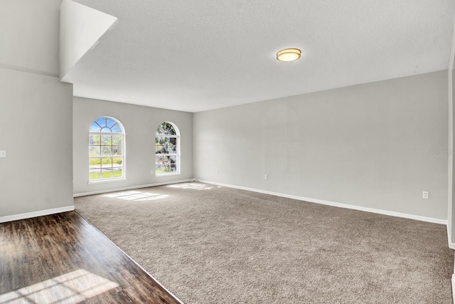 spare room featuring dark colored carpet and a textured ceiling