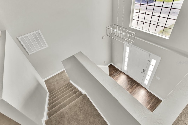 carpeted entrance foyer with a high ceiling and an inviting chandelier