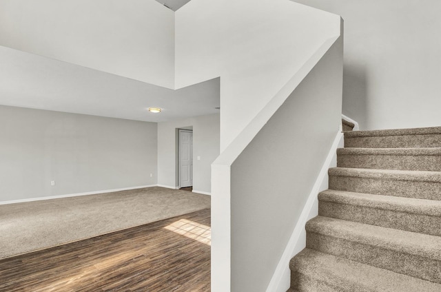 stairway with hardwood / wood-style floors and a towering ceiling