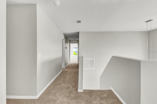 corridor featuring a textured ceiling and light colored carpet