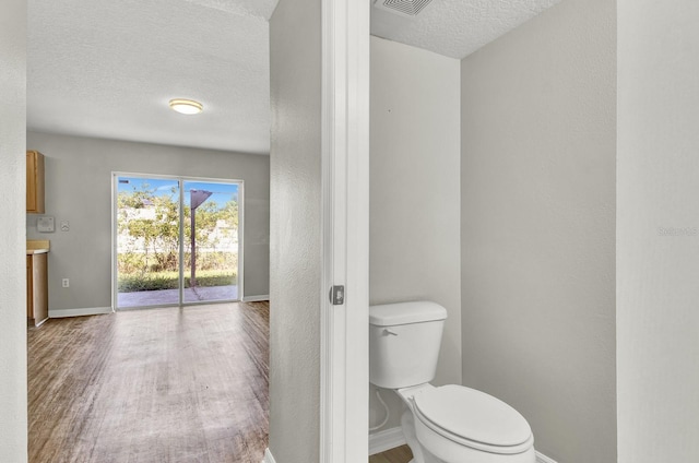 bathroom featuring a textured ceiling, hardwood / wood-style flooring, and toilet