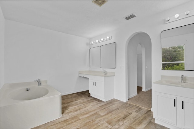 bathroom featuring a tub to relax in, vanity, hardwood / wood-style flooring, and a textured ceiling