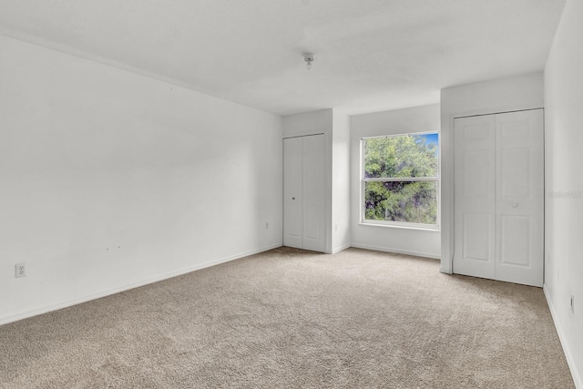 unfurnished bedroom with carpet floors and multiple closets