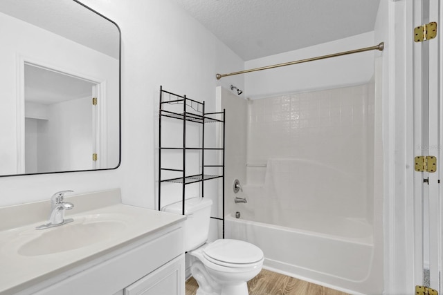 full bathroom featuring  shower combination, toilet, a textured ceiling, vanity, and hardwood / wood-style flooring