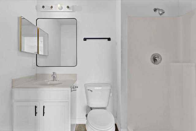 bathroom with vanity, toilet, and tiled shower