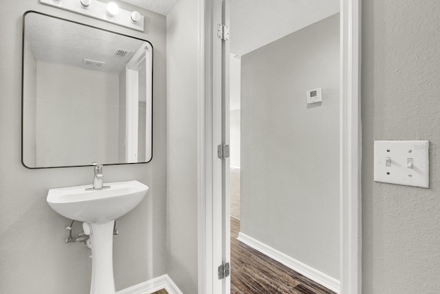 bathroom with a textured ceiling, hardwood / wood-style flooring, and sink