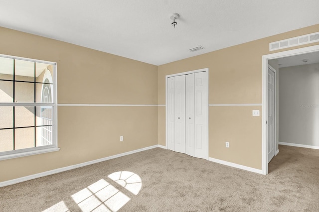 unfurnished bedroom featuring light carpet and a closet