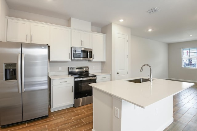 kitchen with sink, white cabinetry, stainless steel appliances, and a kitchen island with sink