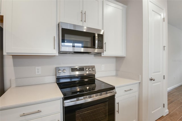 kitchen with white cabinetry, stainless steel appliances, and hardwood / wood-style flooring