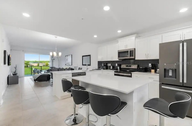 kitchen with appliances with stainless steel finishes, decorative light fixtures, a breakfast bar area, and white cabinets