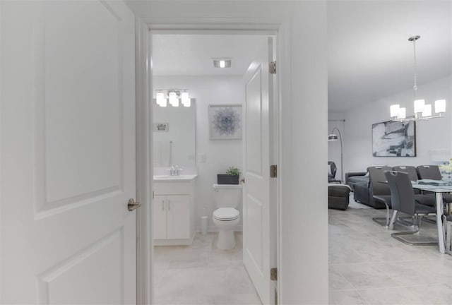 bathroom featuring vanity, toilet, and a notable chandelier