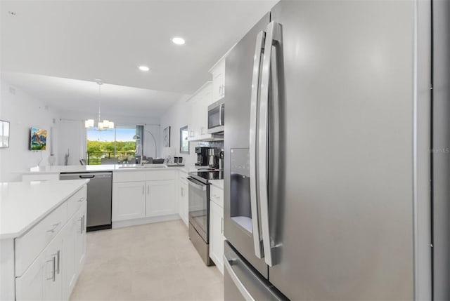 kitchen with pendant lighting, white cabinets, kitchen peninsula, stainless steel appliances, and an inviting chandelier