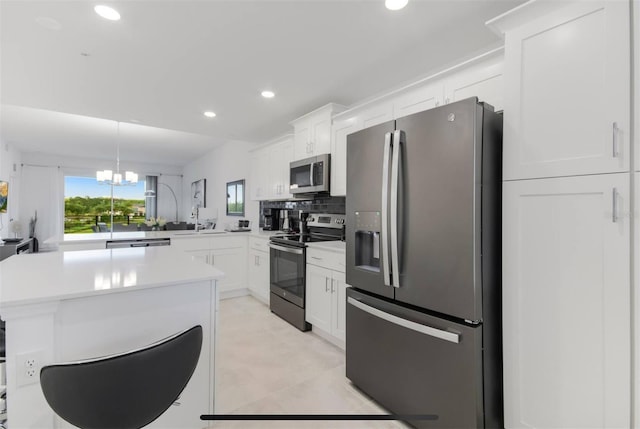 kitchen featuring white cabinetry, appliances with stainless steel finishes, decorative light fixtures, and kitchen peninsula